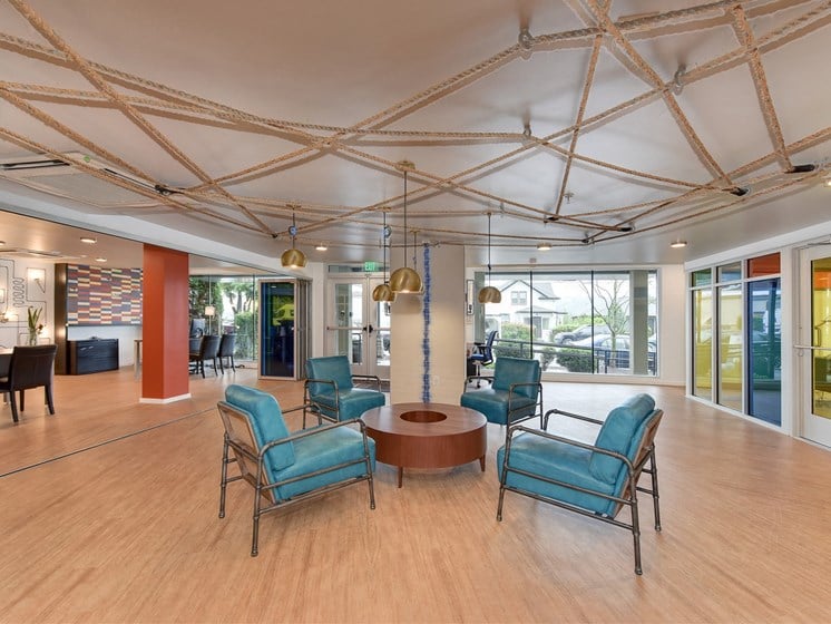Leasing Office with Hardwood Inspired Floor, Blue Sofa Chairs, Hanging Ceiling Lights and Exit Door